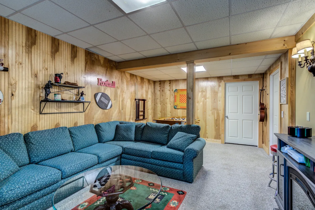 Inside, a blue sectional sofa, glass coffee table, and wood-paneled walls create a relaxed and social environment. Decorative shelves suggest a space for board games and conversation, reinforcing the fun and entertainment options available for groups indoors.