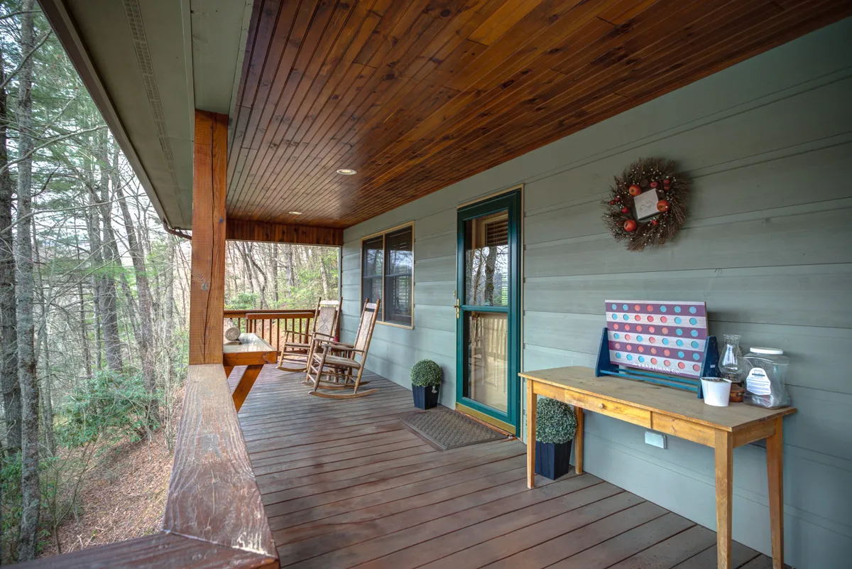 A welcoming porch with classic rocking chairs, a small wooden table, and potted greenery. The porch looks out onto nature, inviting moments of quiet reflection, coffee at sunrise, or simply soaking in the mountain atmosphere.