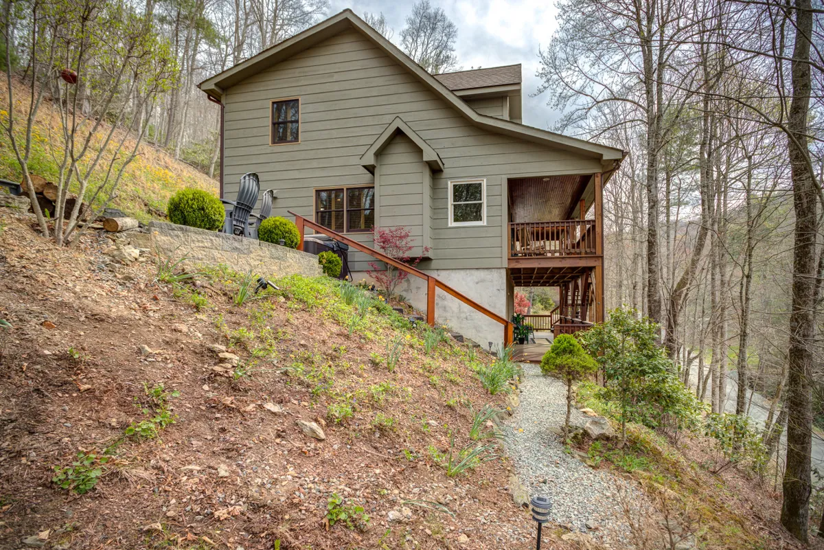 This image shows the cabin nestled among tall trees, with a clear path leading up to the entrance. The surrounding woods evoke a sense of adventure and seclusion, while the cozy porch hints at relaxation after a day outdoors.